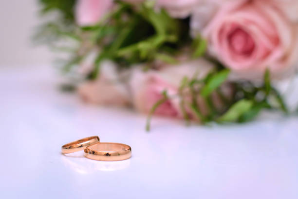 istock Wedding rings on pink background with wedding bouquet 1089639794