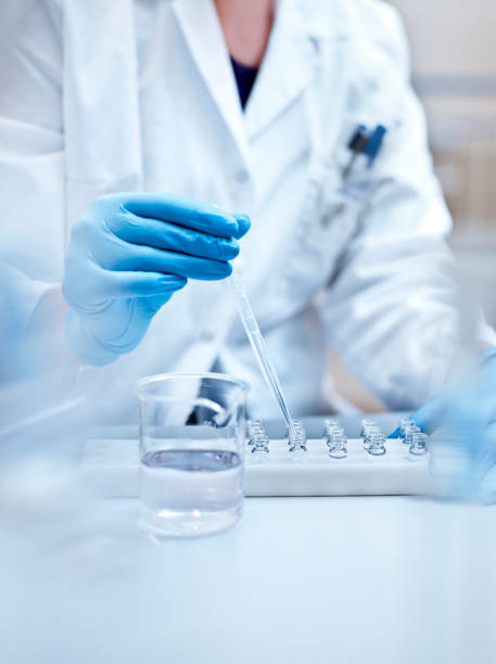 Chemist examining medical solution in laboratory Chemist filling medical solution in vial through pipette. Female scientist is experimenting in laboratory. She is wearing gloves at pharmaceutical factory. pharmaceutical factory stock pictures, royalty-free photos & images