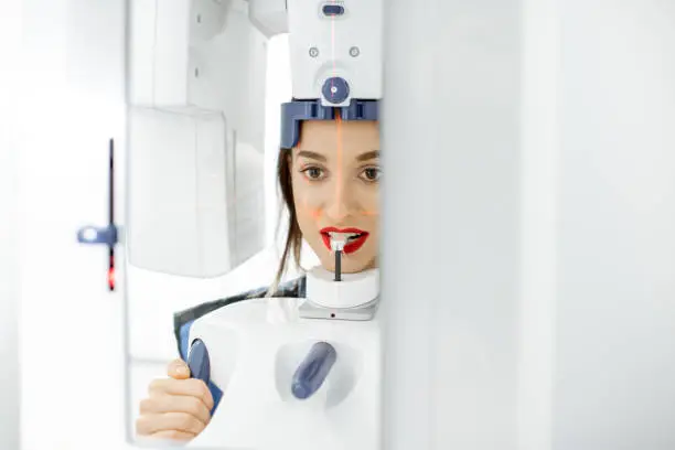 Young woman making panoramic shot of the jaw holding her face at the x-ray machine