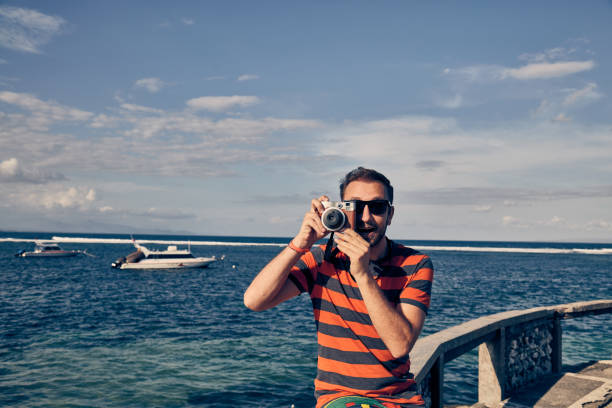 istock Man using vintage film camera on a ocean / sea vacation. 1089648158