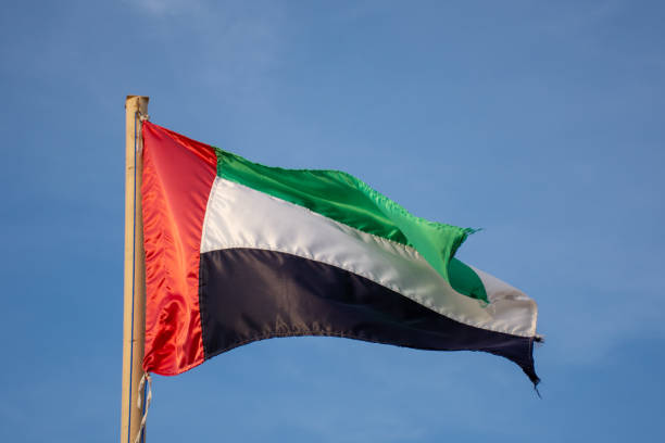 istock UAE flag blowing in the wind with a blue sky background in the bright evening sunshine. 1089657116
