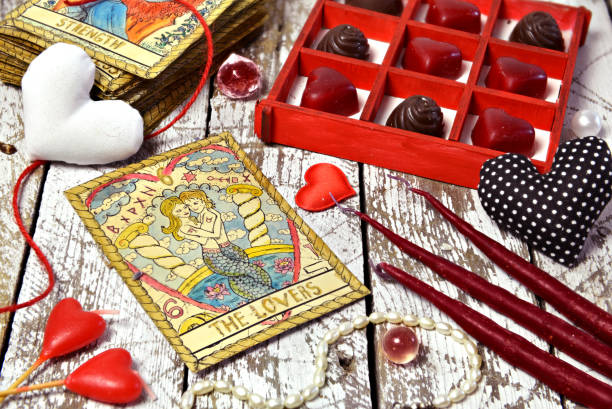 Love magic ritual with red candles, tarot card Lovers, heart symbols and chocolate candies. stock photo