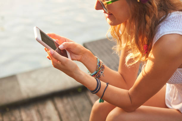 istock Girl using cellphone while lying on a swimming pool deck lounge bed. 1089660238