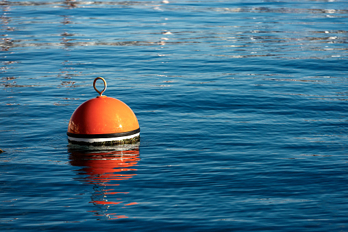 One red and orange buoy for mooring boats on the surface of the water. Mediterranean sea, Italy
