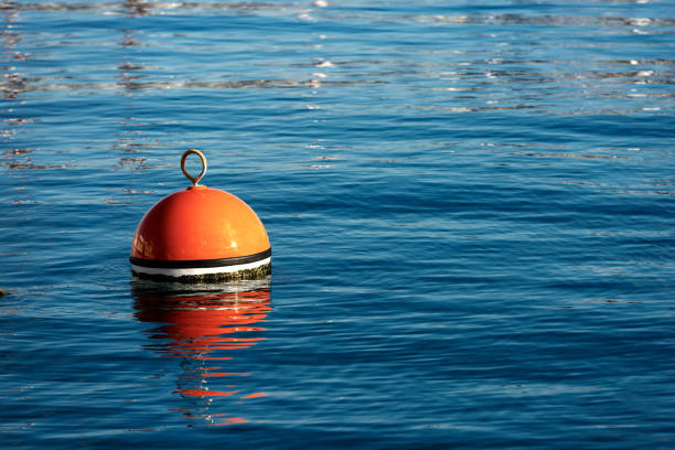 Red and orange mooring buoy in the sea One red and orange buoy for mooring boats on the surface of the water. Mediterranean sea, Italy buoy stock pictures, royalty-free photos & images