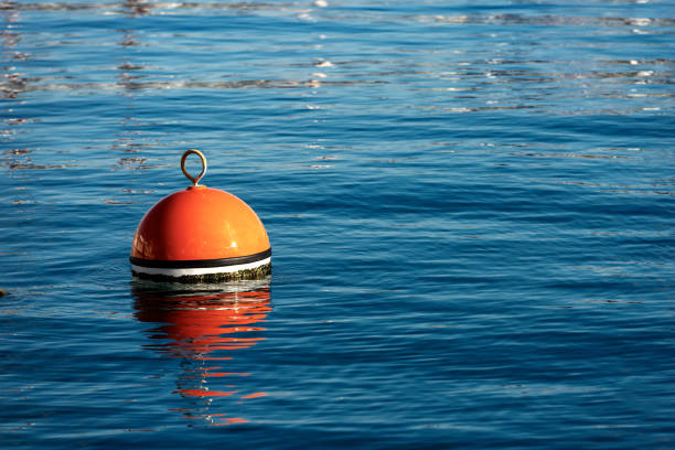 красный и оранжевый швартовной буй в море - buoy anchored sea wave стоковые фото и изображения