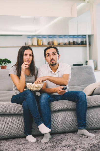 istock Husband and woman sitting on the couch holding popcorn 1089667042