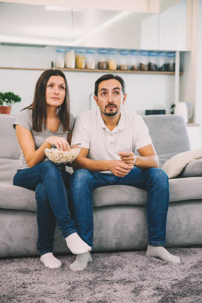 istock Husband and woman sitting on the couch holding popcorn 1089667104