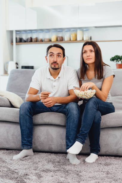 istock Husband and woman sitting on the couch holding popcorn 1089667124