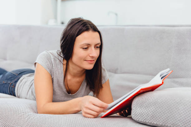 istock A woman reads a book lying on the couch 1089668878