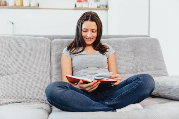 istock Woman sitting on the couch reading a book 1089668954