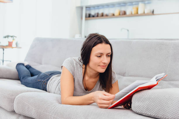 istock A woman reads a book lying on the couch 1089668962