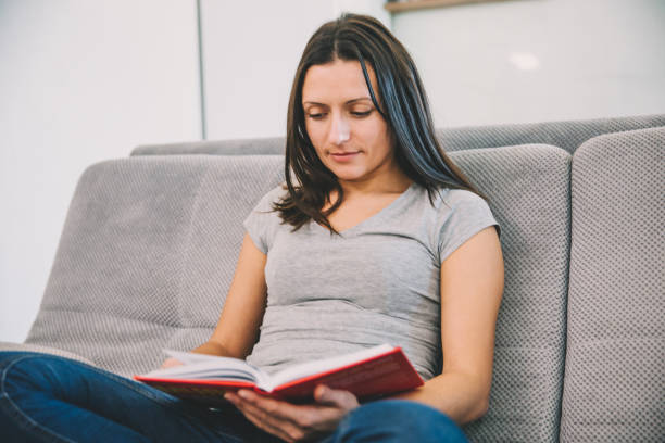 istock Woman sitting on the couch reading a book 1089673604