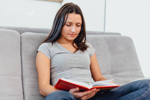istock Woman sitting on the couch reading a book 1089673608
