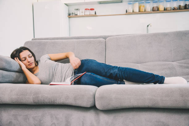 istock A woman reads a book lying on the couch 1089673640