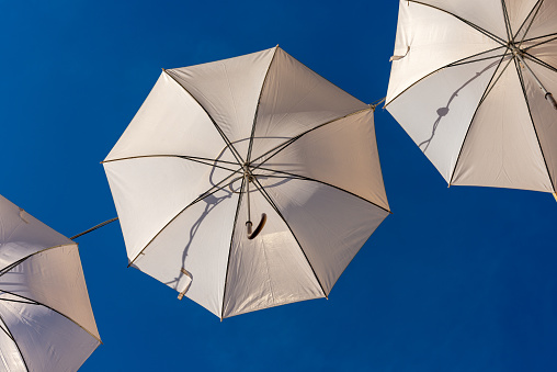 Group of three white umbrellas on a clear blue sky, used as city lighting