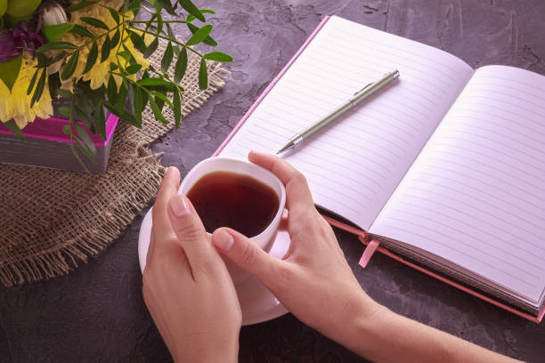istock Tea in female hands next to flowers and notepad 1089676566