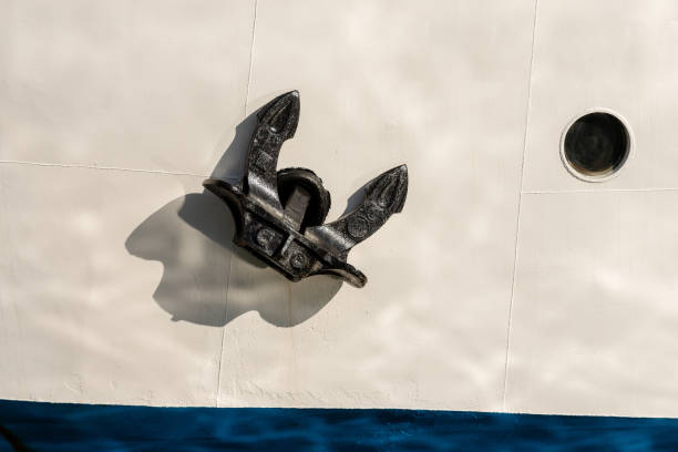 Detail of a white and blue ship prow with a black anchor and a porthole