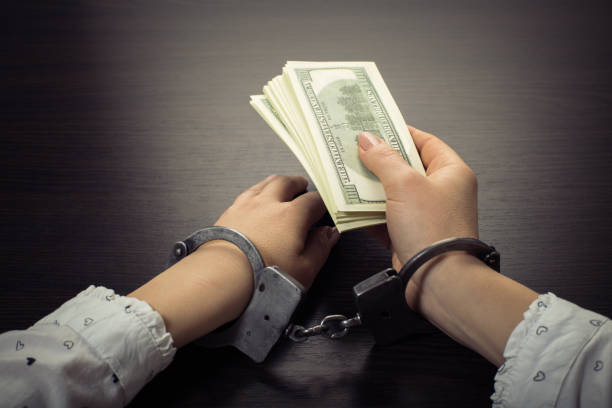 istock hands in handcuffs holding paper money 1089693546