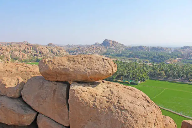 Photo of Green rice fields or terraces in the village of Hampi. Palm trees, sun,rice fields, large stones in Hampi. Tropical exotic landscape. Beautiful green valley. View from above