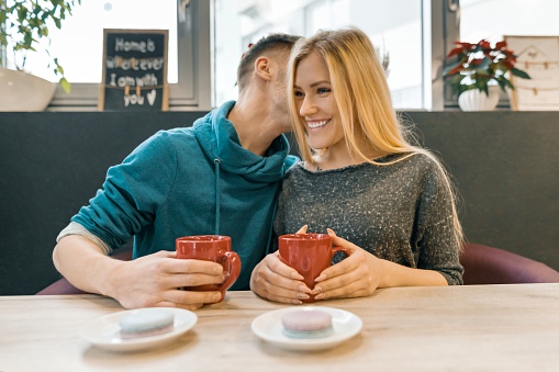 Young happy couple in love in cafe, young man and woman together smile hugging drink coffee tea.