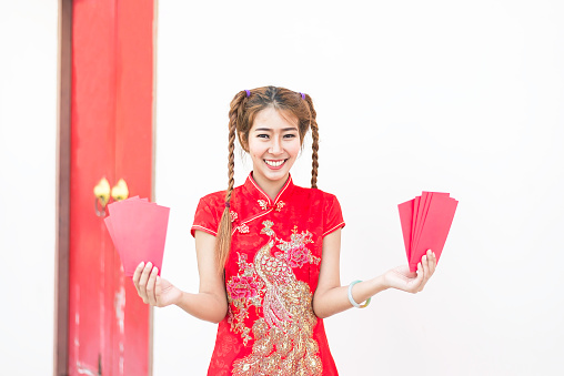 Happy asian woman in traditional chinese dress holding a red pocket with Chinese one hundred Yuan banknotes- lucky money. Tet holiday. Chinese New Year