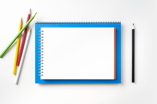 Design concept - Top view of blue and red spiral notebook, white page and pencil isolated on background for mockup
