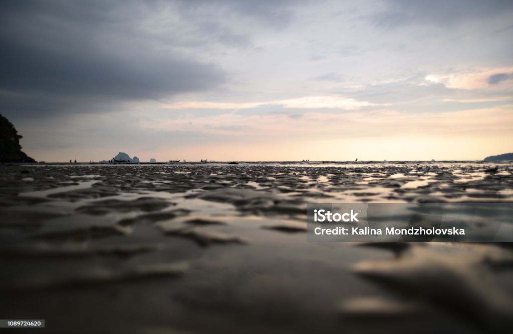 Low tide at Noppharathara Beach The beach as the water retreats, leaving small puddles and bumpy texture, during sunset Ao Nang Stock Photo