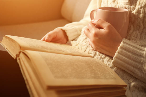 istock young woman holding cup of tea and reading open book 1089725048