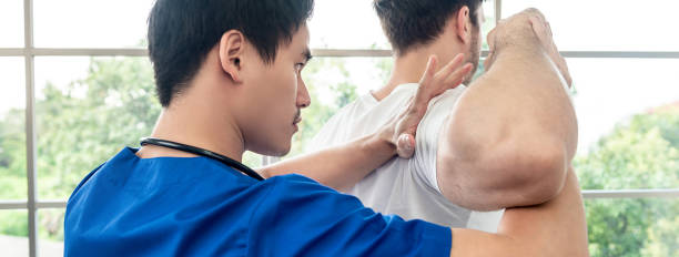 asian physical therapist stretching athlete male patient shoulder and back in clinic - reflexology massaging recovery sport imagens e fotografias de stock