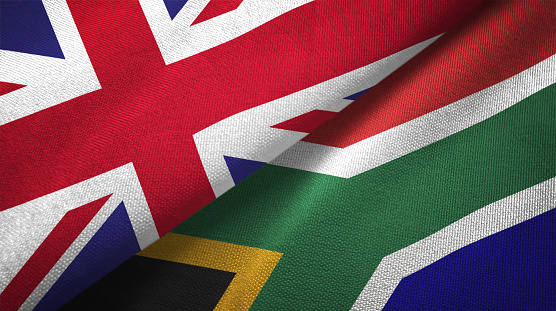 South African flag flies in a strong wind against a mostly clear summer sky.