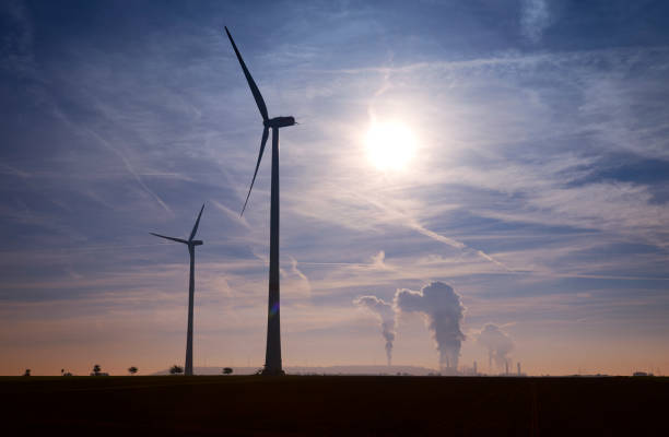 istock Silhouette of a two wind turbines and coal fired power plant 1089734512