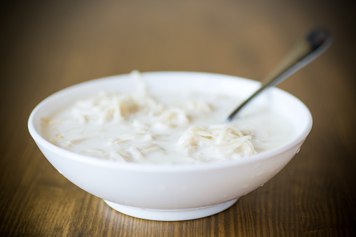 homemade sweet noodles with milk in a plate on a wooden table