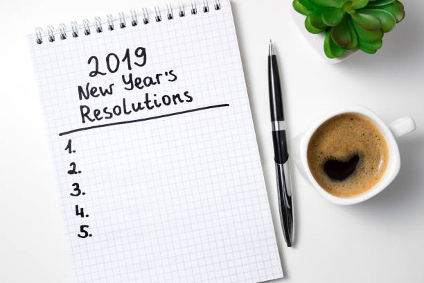 istock New year resolution 2019 on desk. 2019 goals list with notebook, coffee cup and glasses on white background. Goal, plan, strategy, change, idea concept 1089754820