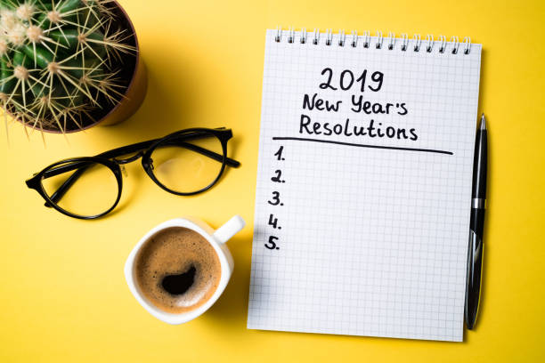 istock New year resolution 2019 on desk. 2019 goals list with notebook, coffee cup and glasses on yellow background 1089754900