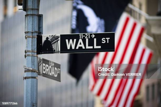 Wall Street Sign With American Flag In The Financial District Of Lower Manhattan Stock Photo - Download Image Now