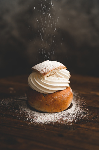 Sprinkling powdered sugar on a traditional Swedish dessert called semlor.