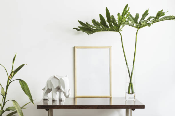 istock The stylish interior with mock up poster frame, leafs and elephant sculpture. The minimalizm concept of space. 1089776896