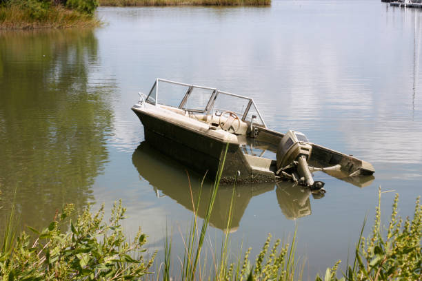 Sunken Boat in a backwater bay in coastal virginia old Sunken Boat in a backwater bay in coastal virginia. In a remote inlet off the Chesapeake Bay, Virginia an old motorboat lays sunken in the tidal mud. A serene nature scene with a story untold. the estuary water is calm and you can see trees and marsh in the background. The clouds of the summer sky are reflected in the marine water. - A great coastal, shot taken in the outdoors. tidal inlet stock pictures, royalty-free photos & images