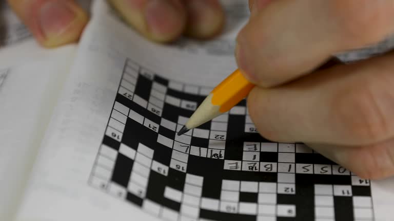 brain training - hand doing crossword puzzle closeup