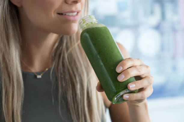Wheatgrass Unrecognizable woman is about to drink a green healthy smoothie. antioxidant stock pictures, royalty-free photos & images