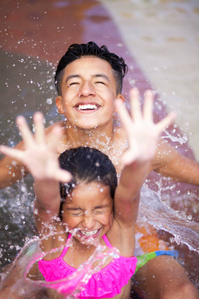 niños sentados en la piscina jugando con agua - swimming pool water people sitting fotografías e imágenes de stock