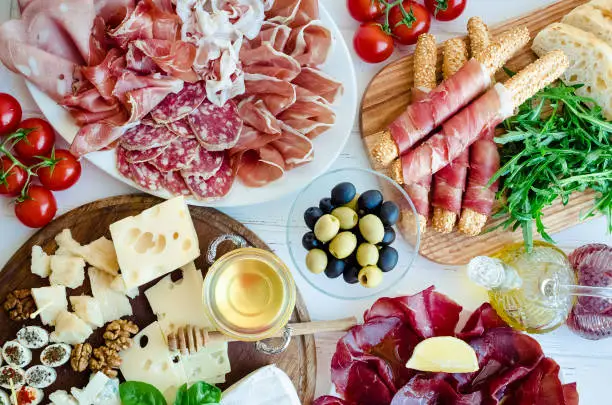 Table full of mediterranean appetizers, tapas or antipasto. Assorted Italian food set. Delicious snack on party or picnic time. Chopping board with meat and cheese. Italian style banquet. Top view.