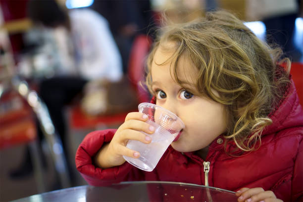 istock Little girl drinking water from a glass 1089797512