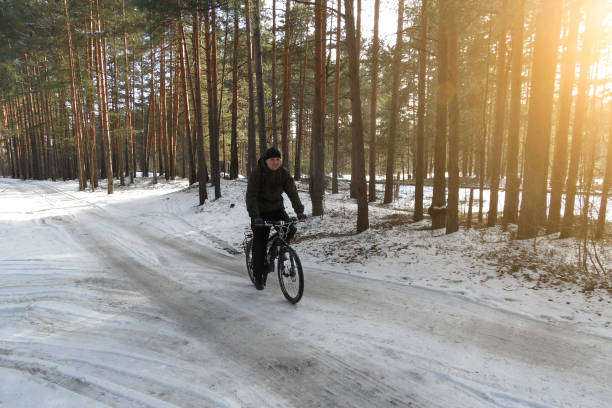 istock cyclist without a helmet rides on snow-covered forest road on Bicycle on Sunny spring day 1089807024