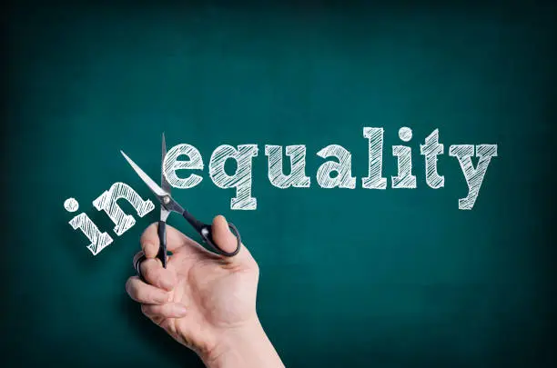 The male hand with scissors cuts word Equality from Inequality