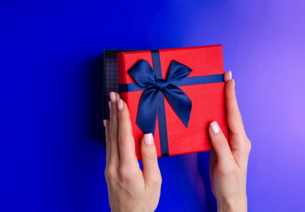 istock Red box gift with blue ribbon in hand on blue background 1089813816