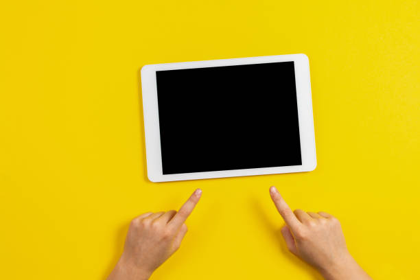 istock Kid hands finger pointing to tablet computer on yellow background 1089818832