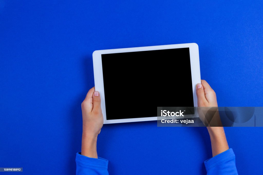 Kid hands with tablet computer on blue background Kid hands with tablet computer on blue background. Digital Tablet Stock Photo