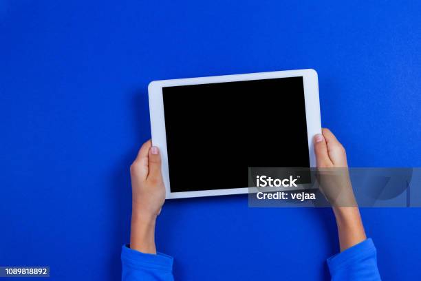 Kid Hands With Tablet Computer On Blue Background Stock Photo - Download Image Now - Digital Tablet, Drawing Board, Graphics Tablet